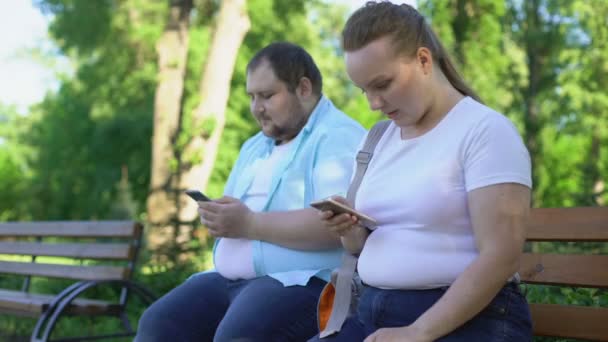 Толстая пара выкладывает фотографии в соцсети, расстроенная девушка ждет лайков — стоковое видео