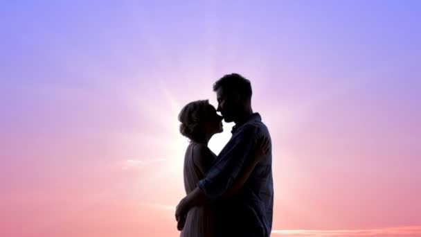 Casal apaixonado abraçando calorosamente contra o nascer do sol brilhante, sentimentos ternos, beijos — Vídeo de Stock