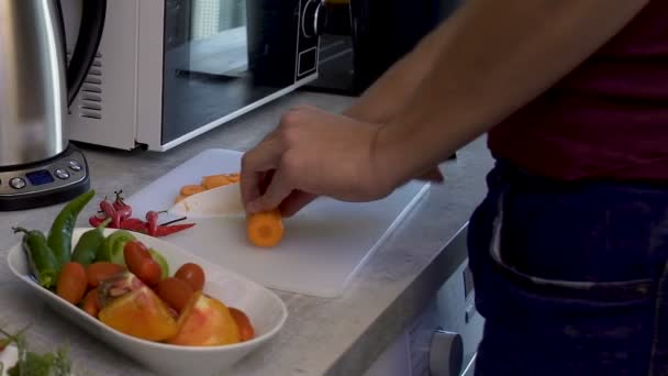 Uomo sportivo che taglia verdure per insalata, saluta gli ospiti, alimentazione dietetica — Video Stock