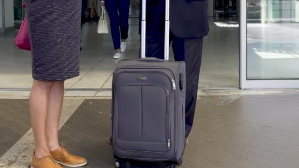 Personas con maletas que salen del aeropuerto, llegada después de un viaje de negocios, vacaciones — Vídeo de stock