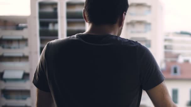 Homme bouleversé regardant le quartier depuis le balcon de l'étage supérieur, réfléchissant sur les dettes — Video