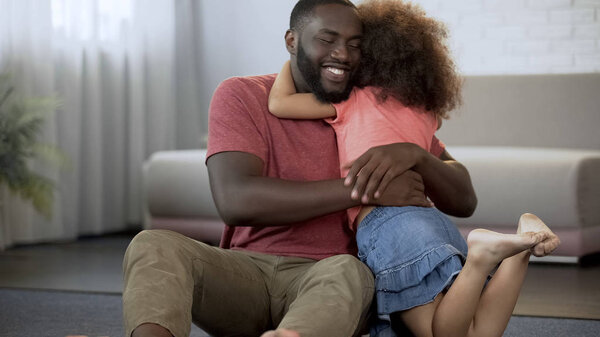 Маленькая дочь крепко обнимает любимого папочку, отличные отношения в семье
