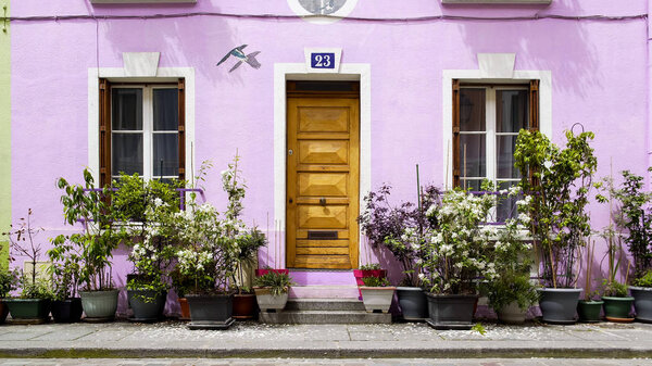 Красивый фиолетовый дом, украшенный цветами, красивая улица в Париже, Франция
