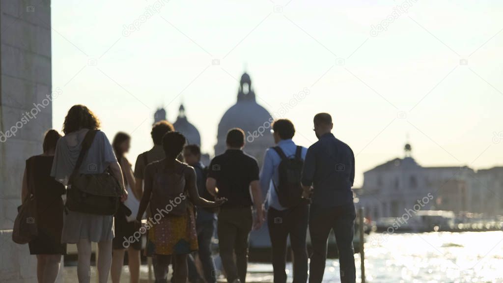 Group of multi-ethnic tourists walking in Venice, view of Grand Canal, tourism