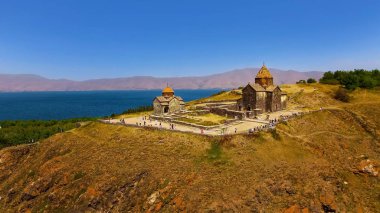 Tourists walking near ancient Surp Arakelots and Astvatsatsin churches, Armenia clipart