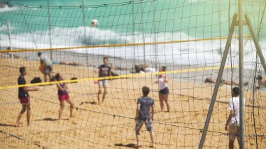 Genç aktif insanlar kum plajındaki arkadaşlar için takım sporu voleybol oynarken