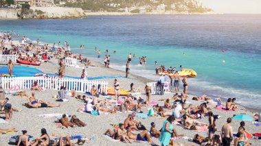 Deniz kıyısında kalabalık halk plajı, birçok kişi güneş bronzlaşma, su sıçrayan