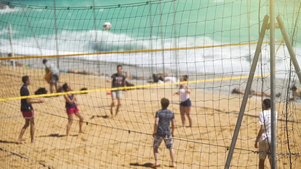 Genç aktif insanlar kum plajındaki arkadaşlar için takım sporu voleybol oynarken