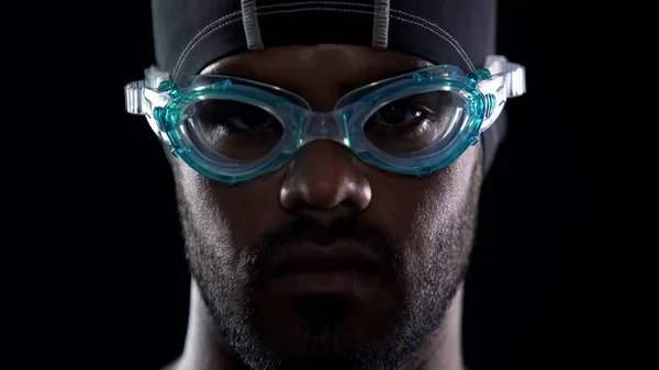 Determined face of male swimmer in goggles looking into camera close-up, sport