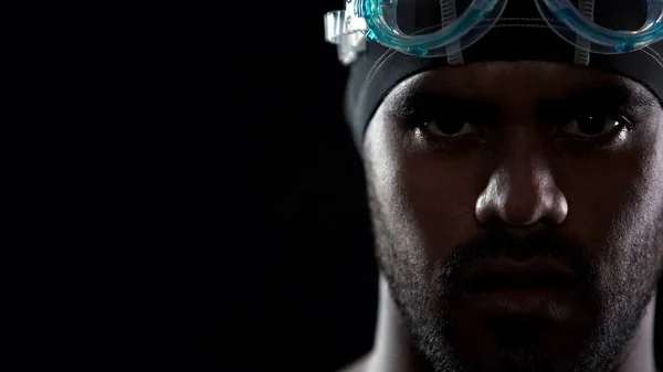 Masculine Hispanic swimmer wearing goggles, looking directly into camera, sport