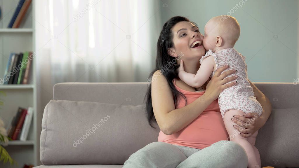 Cute toddler girl kissing and hugging her mother, love and tenderness in family