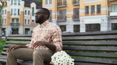 Çiçekler, görücü usulü ile park bankında oturan kız için bekleyen sinirli genç adam