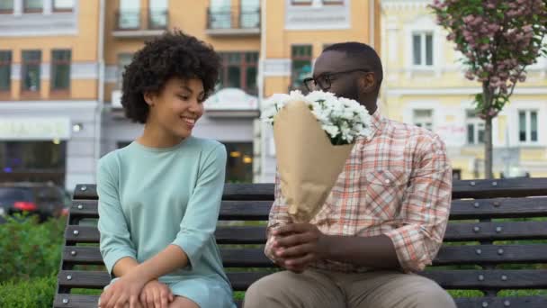 Jonge Man Met Witte Bloemboeket Tot Vrouw Vergadering Bank Eerste — Stockvideo