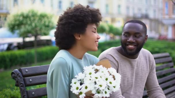 美しいアフリカの女の子を抱いて甘いカップル日に花で幸せな気持ち — ストック動画