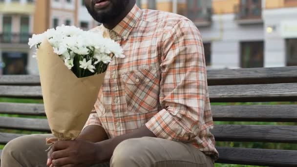Zdenerwowany Mężczyzna Siedzi Ławce Gospodarstwa Kwiaty Próżno Czekając Dziewczyna — Wideo stockowe