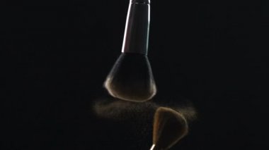 Makyaj fırçaları koyu arka plan üzerinde toz havada, kozmetik sanayi kırıntısı.