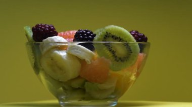 Masanın üstünde, vitaminized tatlı salata etrafında dönen cam kabın içinde taze meyve