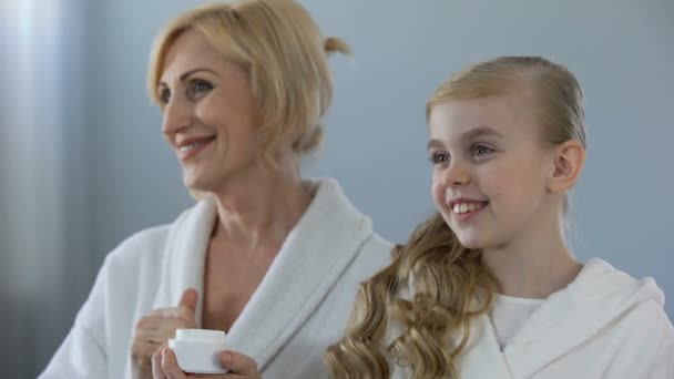 鏡の反射 滑らかな表皮効果 クリームを眺めおばあちゃんと女性の子供 — ストック動画