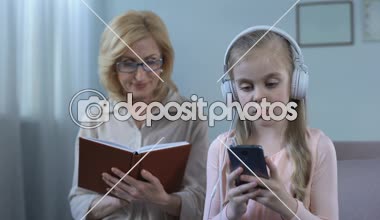 Kız müzik ve Büyükanne kitap okumak, kuşak çatışması dinlerken kulaklık