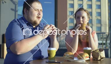 Tombul erkek ve kadın burgers ve fries, meslektaşları dışarıda yemek yeme