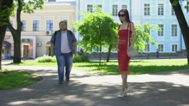 Genç güzel kız şişman adam görmezden Park, ince Bayan konuşan adam kilolu