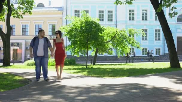 美しい女性と公園 余暇の時間で歩いて手を繋いでいるデブ男 — ストック動画