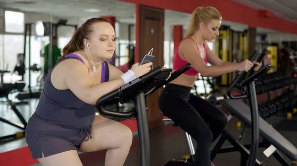 Obez Kadın Tembel Spor Salonunda Sabit Bisiklet Sürme Sırasında Telefonda — Stok fotoğraf