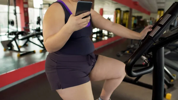 Толстая Женщина Едет Медленный Велосипед Упражнения Смотреть Видео Мобильный Телефон — стоковое фото