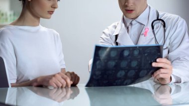 Male doctor explaining young lady results of mammogram, breast cancer awareness clipart