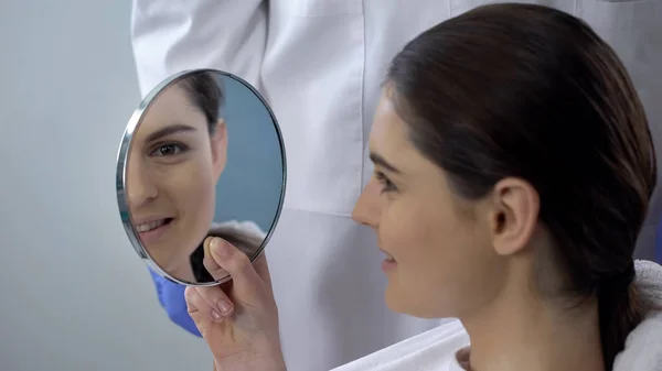 Молодая Женщина Довольна Результатом Ринопластики Улыбающееся Лицо Отражается Зеркале — стоковое фото