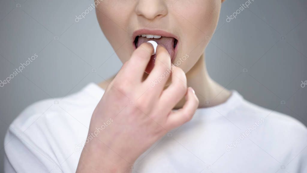 Young lady taking pill, medication treatment prescribed by doctor, vitamins