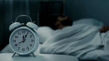 Yatakta, çalar saat gösteren gece yarısı, geri kalan saat, sağlıklı uyku uyuyan adam