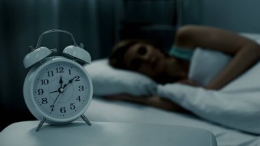 Genç bayan yatağında dinleniyor, gece yarısı çalar saat ile gösteriliyor, gece rüyaları.