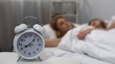 Genç Çift alarm zil ile yatakta uyuyan masada, uyku biorhythms saat