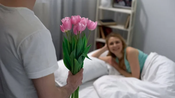 Молодий Чоловік Дарує Тюльпани Сонної Дружини Вранці Доставка Квітів — стокове фото