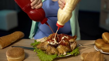 Obese girl pouring unhealthy ketchup and mayonnaise on fatty roast chicken clipart