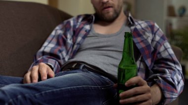 Kanepede oturan ve şişelenmiş bira, para sorunları içme sarhoş adam depresif