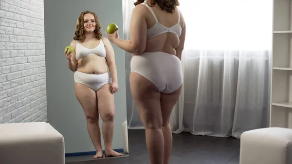 Plump girl chooses healthy food, enjoying her progress in weight loss dieting