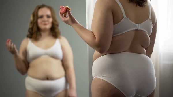 Толстая Молодая Женщина Ест Перед Зеркалом Ненавидя Свое Жирное Тело — стоковое фото