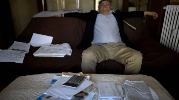 Man lying on couch after checking accounts, family budget, shocked by debt