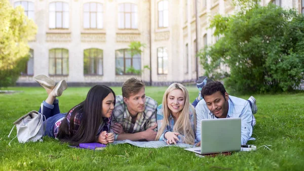 Multietnické Studenti Leží Trávě Dívají Vtipné Video Notebooku Přátel — Stock fotografie