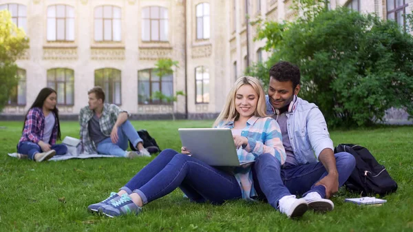 Wieloetnicznego Studentów Siedząc Trawie Oglądania Zabawne Wideo Laptopie — Zdjęcie stockowe