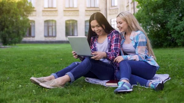 Dwóch Studentów Kobieta Siedzi Trawie Śmiejąc Się Zdjęcia Laptopie Zakupy — Zdjęcie stockowe