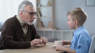 Torunu komik hikayeler anlatmak büyük aile eğlence fincan kakao üzerinde