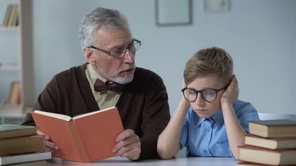 Avô Lendo Voz Alta Livro Menino Parece Entediado Problema Gap — Vídeo de Stock