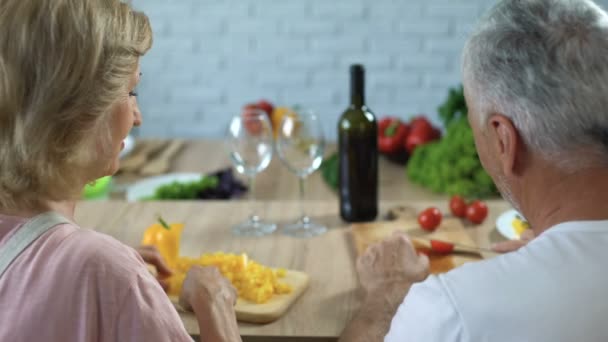 ロマンチックな男眼鏡 幸せなカップルの家で一緒に料理に赤ワインを注ぐこと — ストック動画