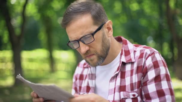 Åldrande Mannen Glasögon Försöker Läsa Tidningen Park Långsynthet Närsynthet — Stockvideo