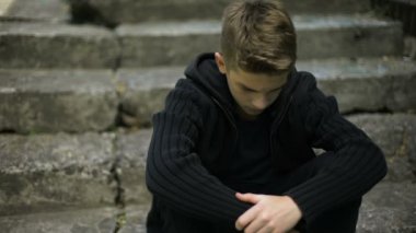 Eski kırık basamaklarında oturan korkmuş yalnız çocuk yankıları savaş, hayat yasta