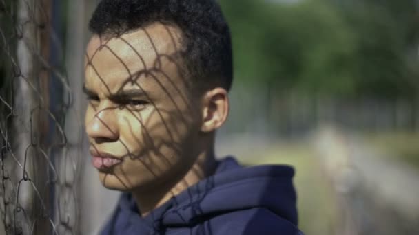 Afro American Pojke Tittar Rika Stadsdelen Genom Stängslet Fattigdom Invandring — Stockvideo