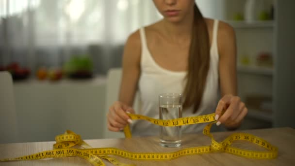 女の子 テープが付いている水のガラスを測定体 食欲不振を飢えています — ストック動画